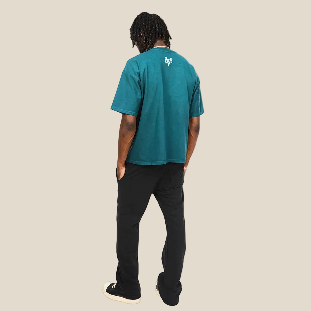 Person wearing a teal t-shirt with a logo on the back, standing against a plain background